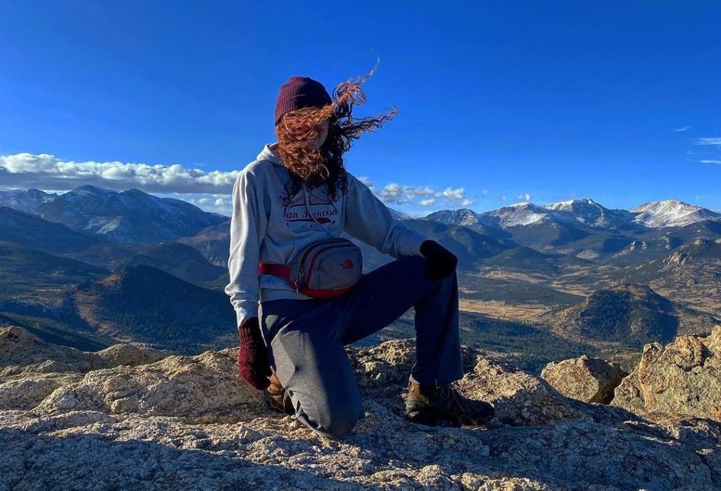 Trinity kneeling on a mountain in Rocky Mountain National Park
