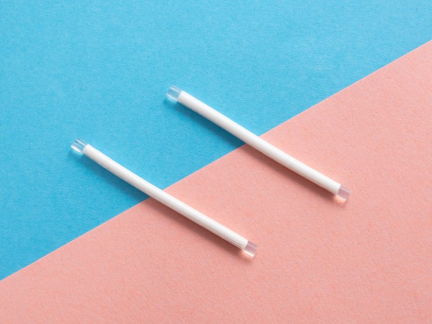 Two implant birth control rods on a tiled pastel background